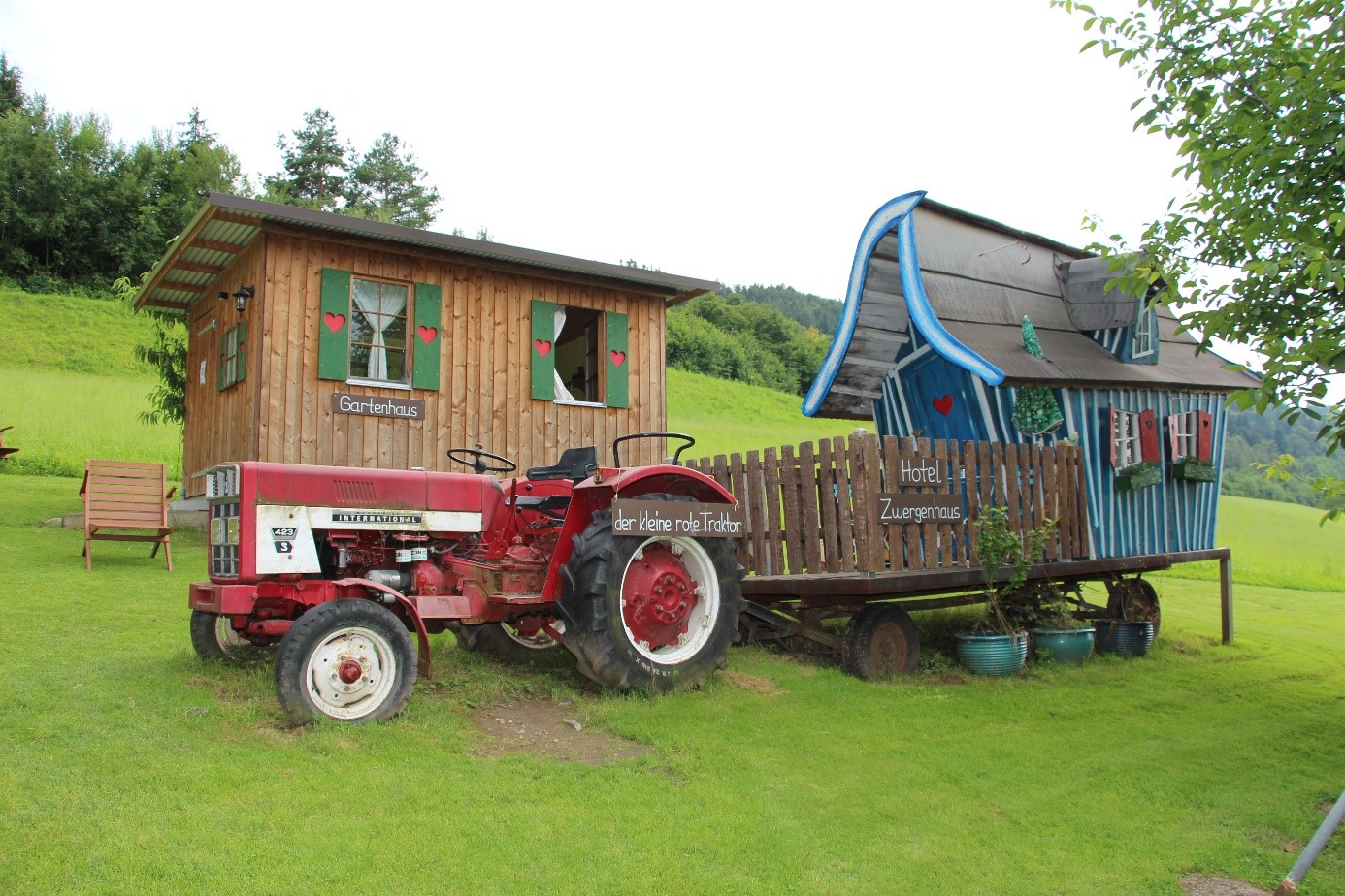 Ein Hotel-Häuschen mit einem Gartenhaus und einem roten Traktor.